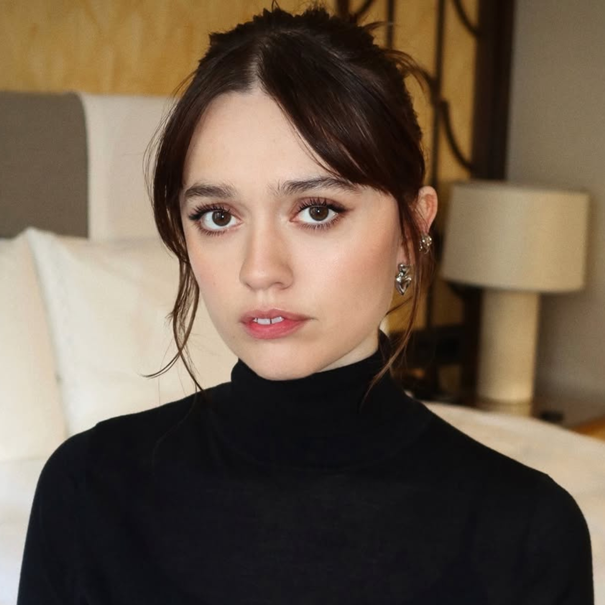 Aimee Lou Wood's glossy brunette updo in a hotel room posing