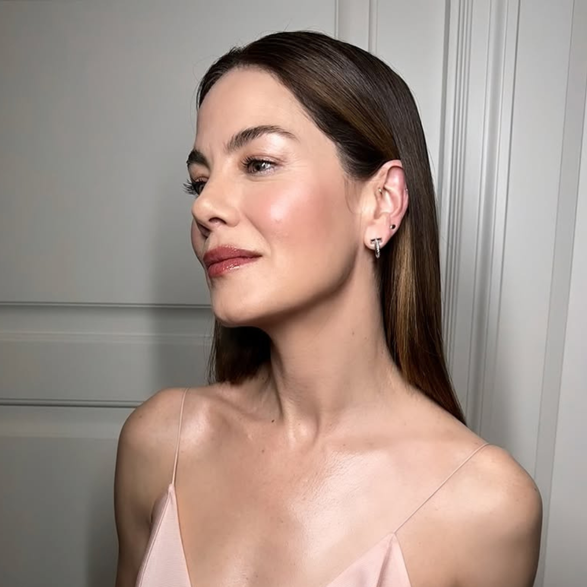 Michelle Monaghan’s moody brunette color shift with cool, natural depth in a pastel pink dress