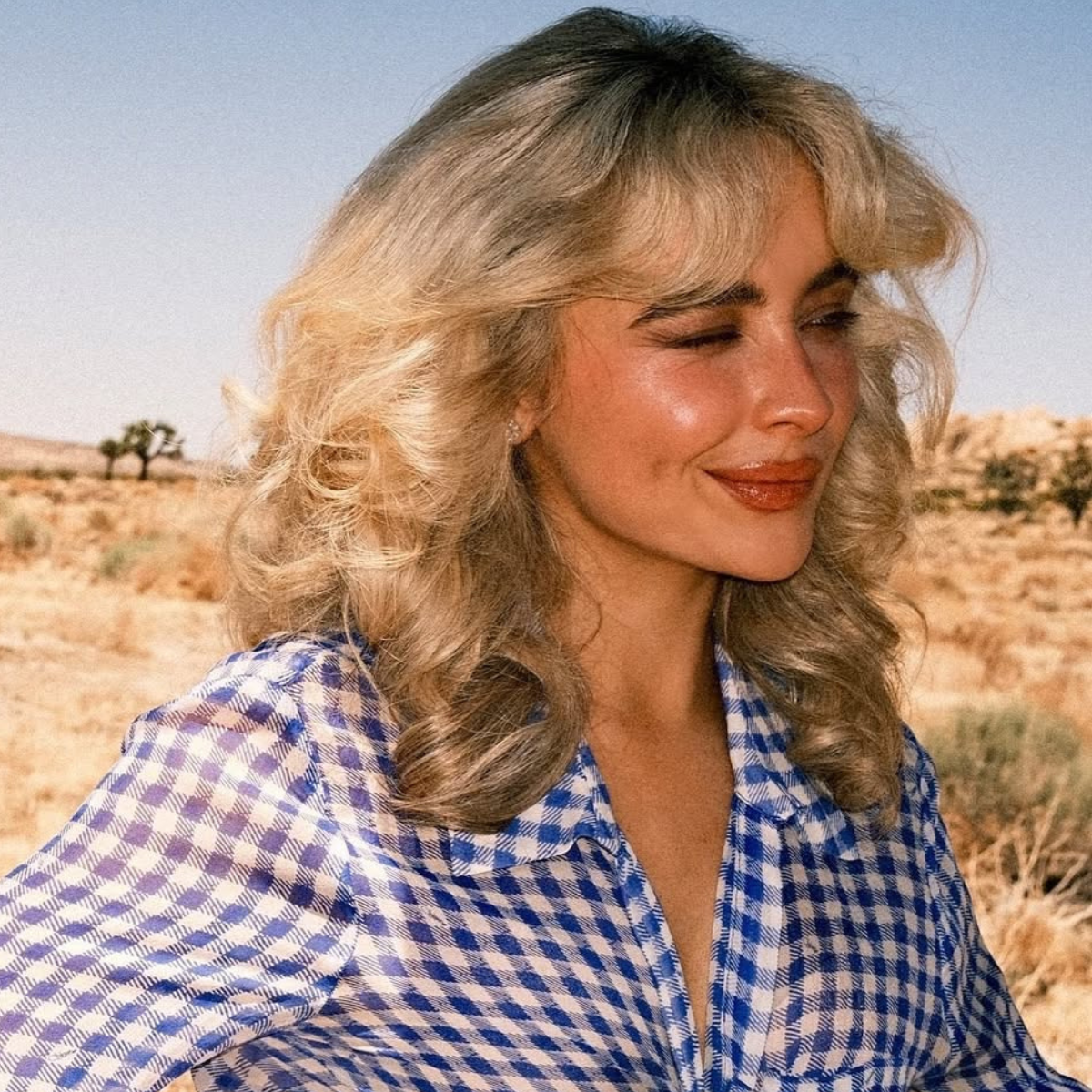 Sabrina Carpenter with full, bouncy buttery blonde blowout and curtain fringe in the desert for “Manchild.”