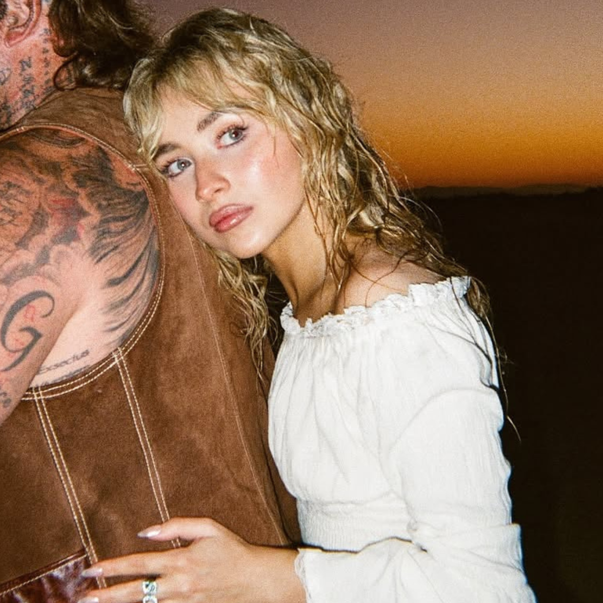 Sabrina Carpenter with tousled buttery blonde waves and curtain bangs at sunset in the “Manchild” music video.