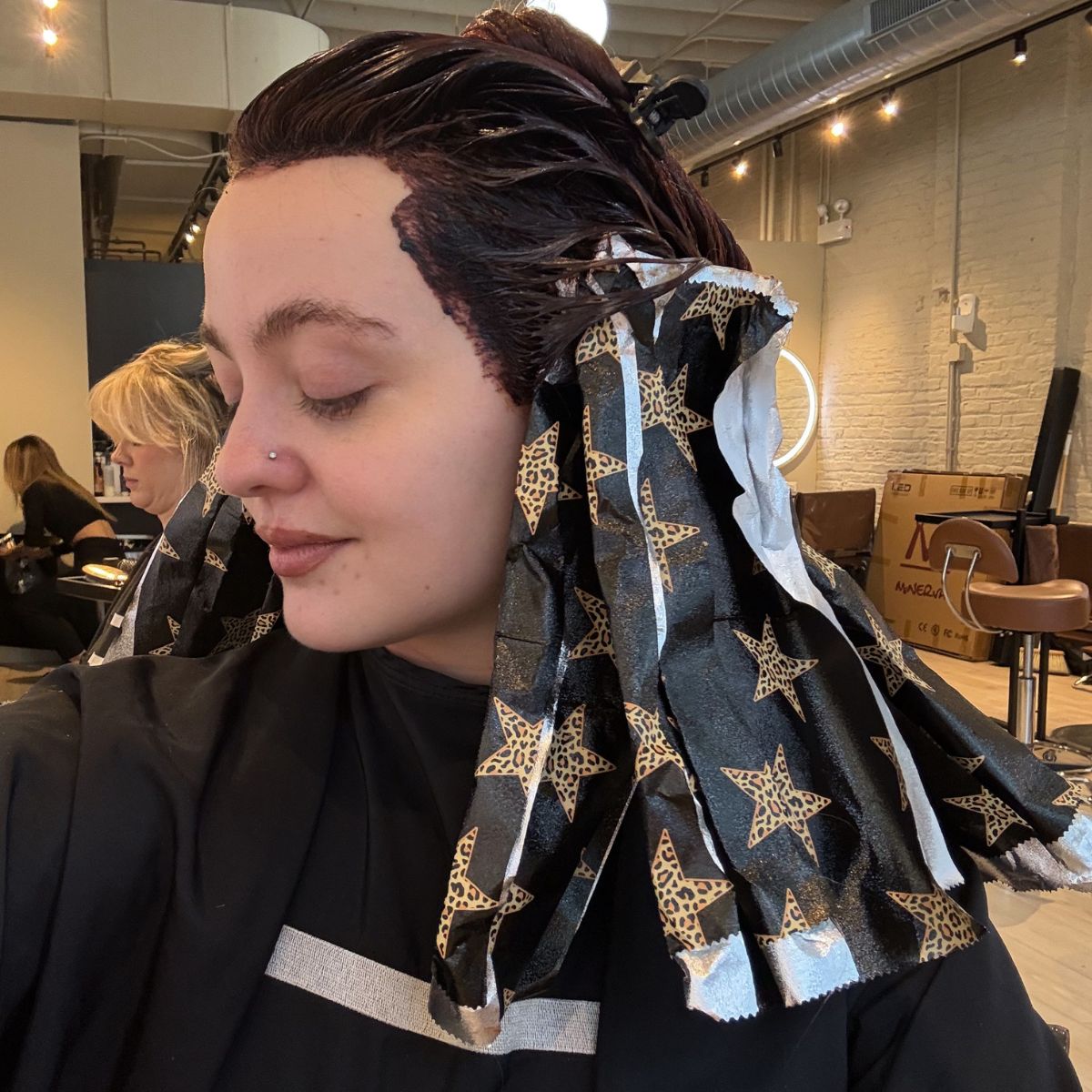 Client during color service with foils applied around the face for dimensional color placement.