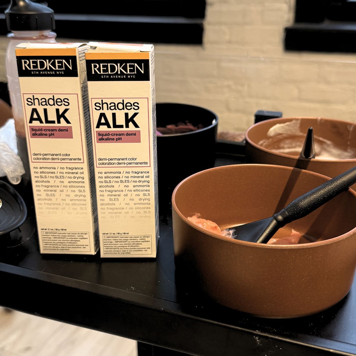Redken Shades EQ products displayed next to color bowls used for toning and glossing.