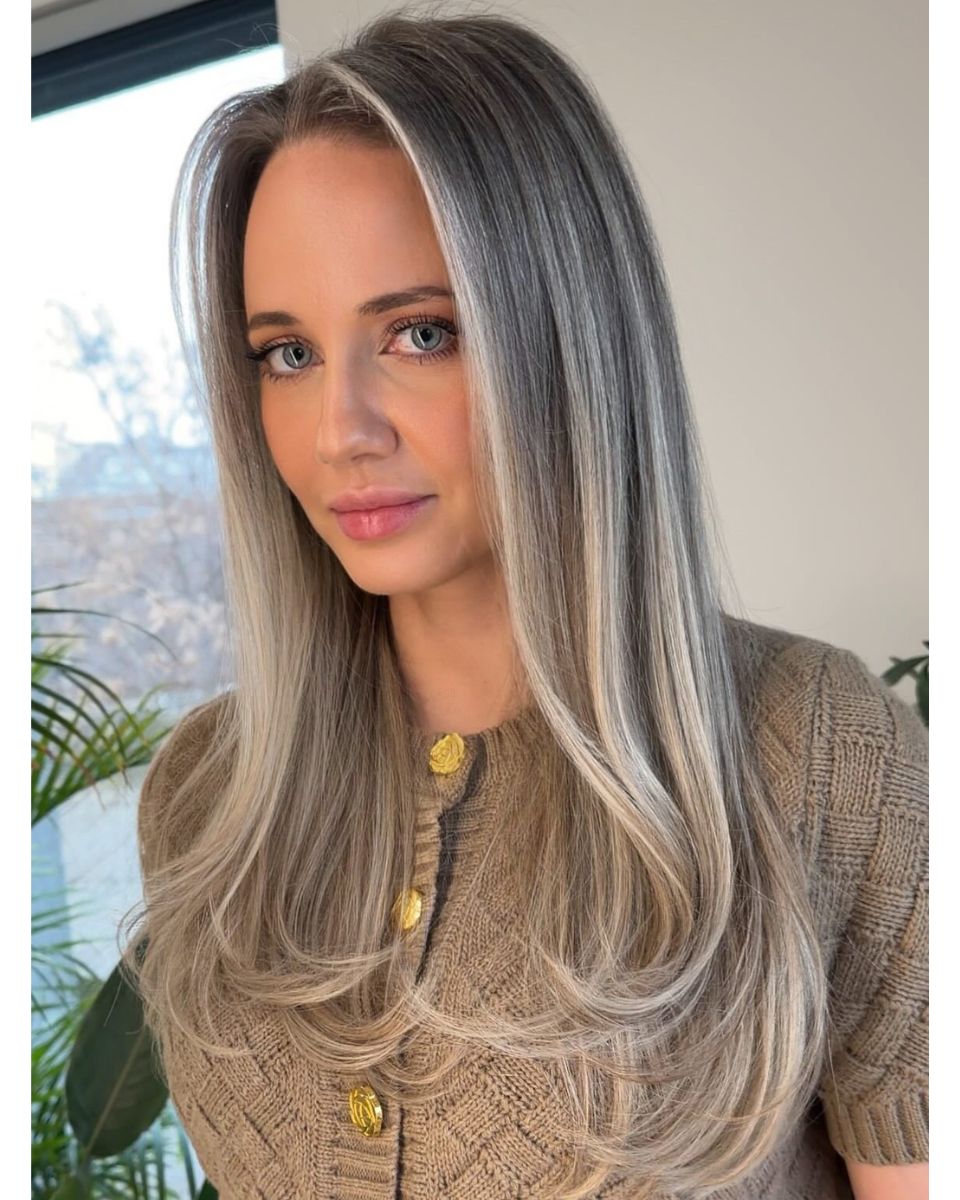 Dimensional ash beige blonde with soft grey blending, face-framing brightness and long layered styling.