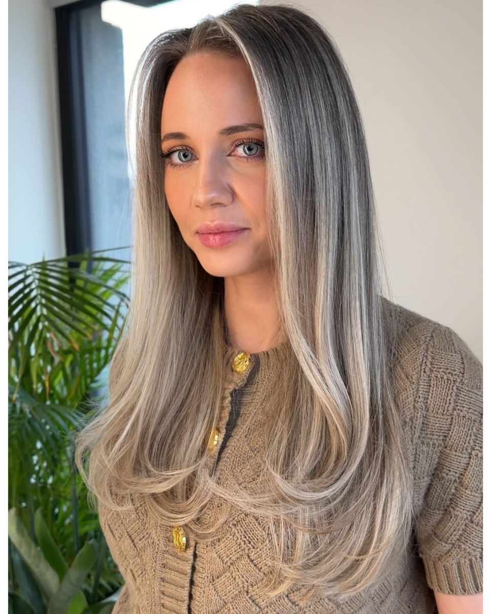 Dimensional ash beige blonde with soft grey blending, face-framing brightness and long layered styling.